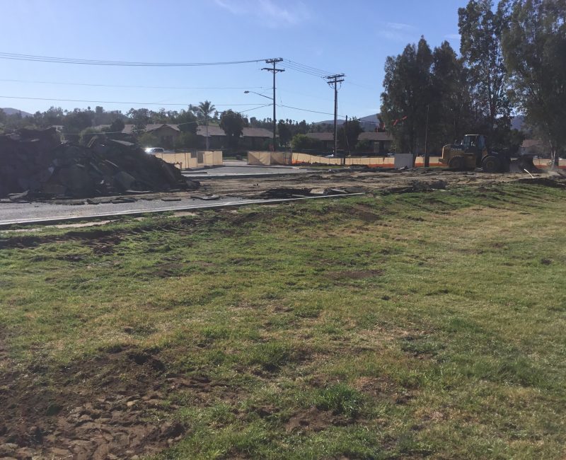 Bulldozer, debris, and houses at a sunny construction site.