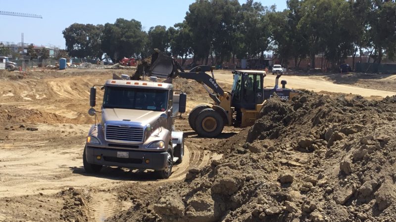 Bulldozer loading dirt into dump truck at construction site.