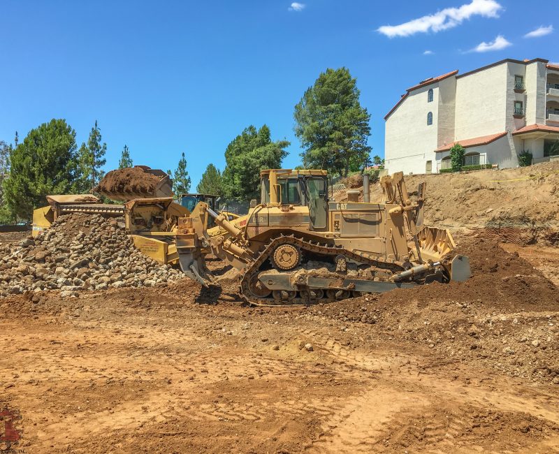 Yellow bulldozer moves dirt at sunny construction site.