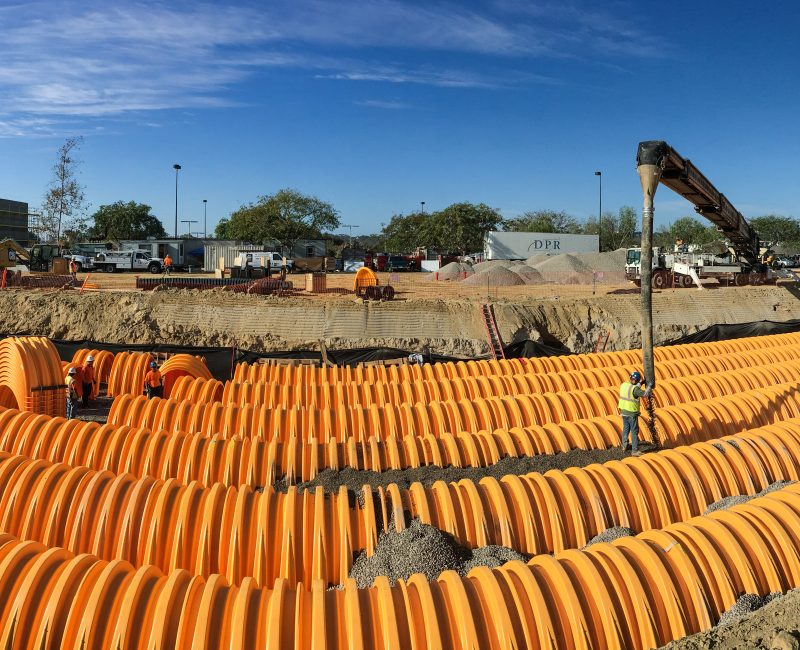 Construction site with orange drainage pipes in a trench.