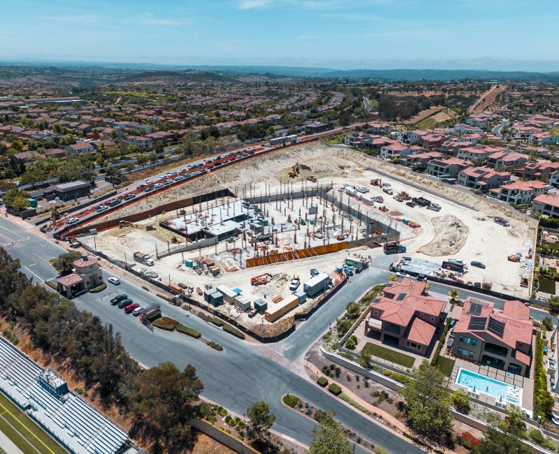 Aerial view of construction site with houses, beams, and vehicles.