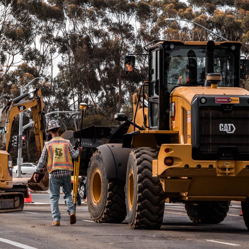 Construction worker walks between CAT bulldozer and excavator.