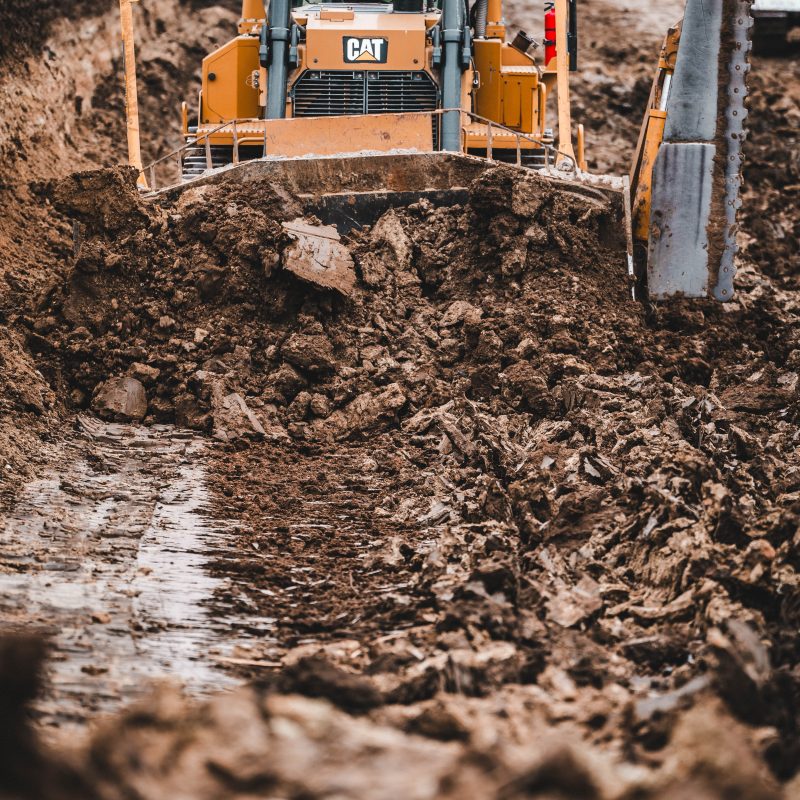 Yellow Caterpillar bulldozer pushes dirt at a construction site.