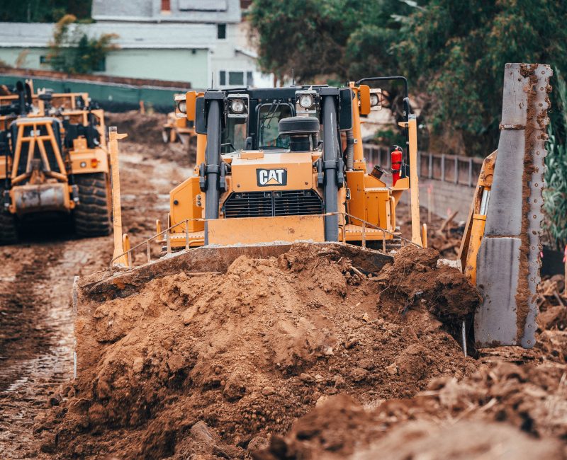 Yellow bulldozers working on a muddy road at construction site.