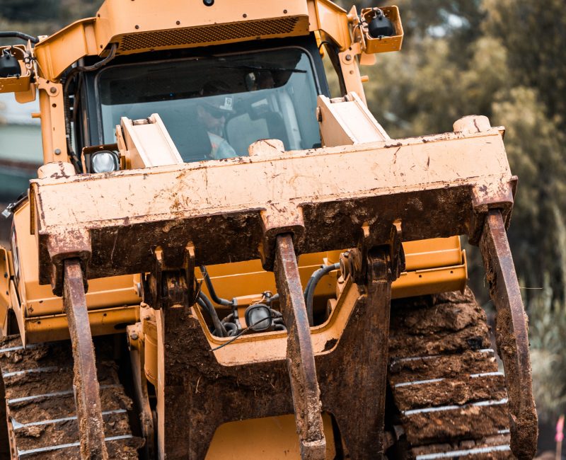 Yellow bulldozer with muddy tracks at a construction site.