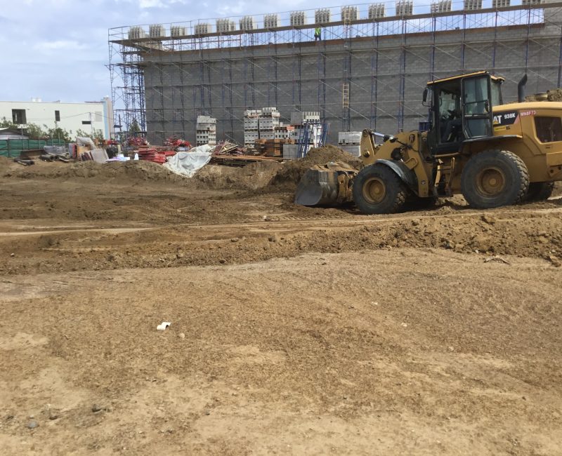 Yellow bulldozer moves dirt at construction site under cloudy sky.