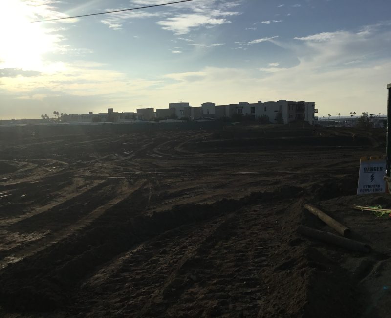 Construction site, tire tracks, dumpster, warning sign, cloudy sky.